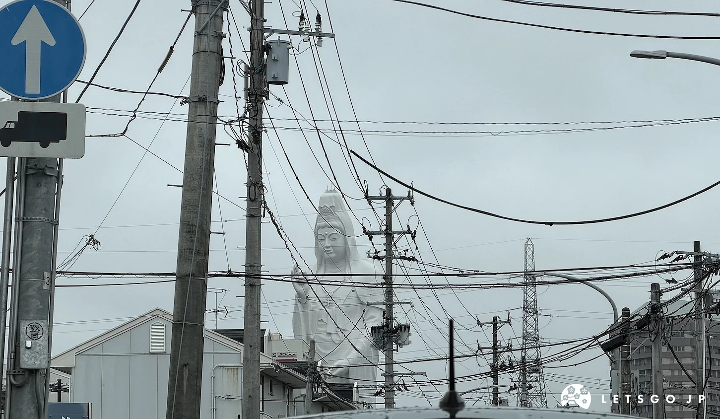 交通標誌與電線後方遠遠現身的觀音像