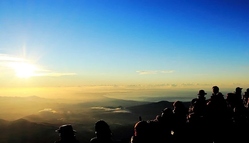 在富士山頂欣賞日出的登山客們