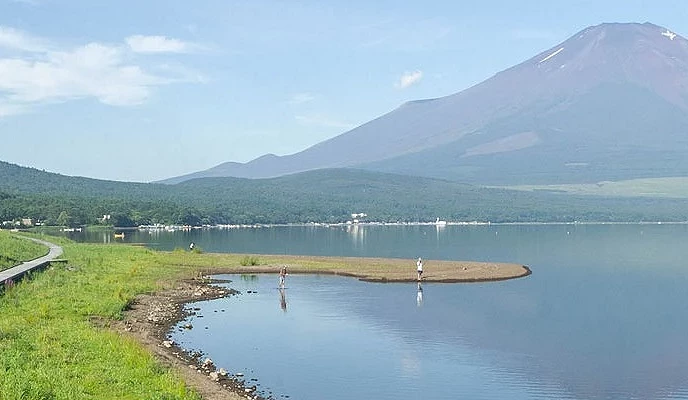 富士山倒映湖面,岸邊遊客與草地