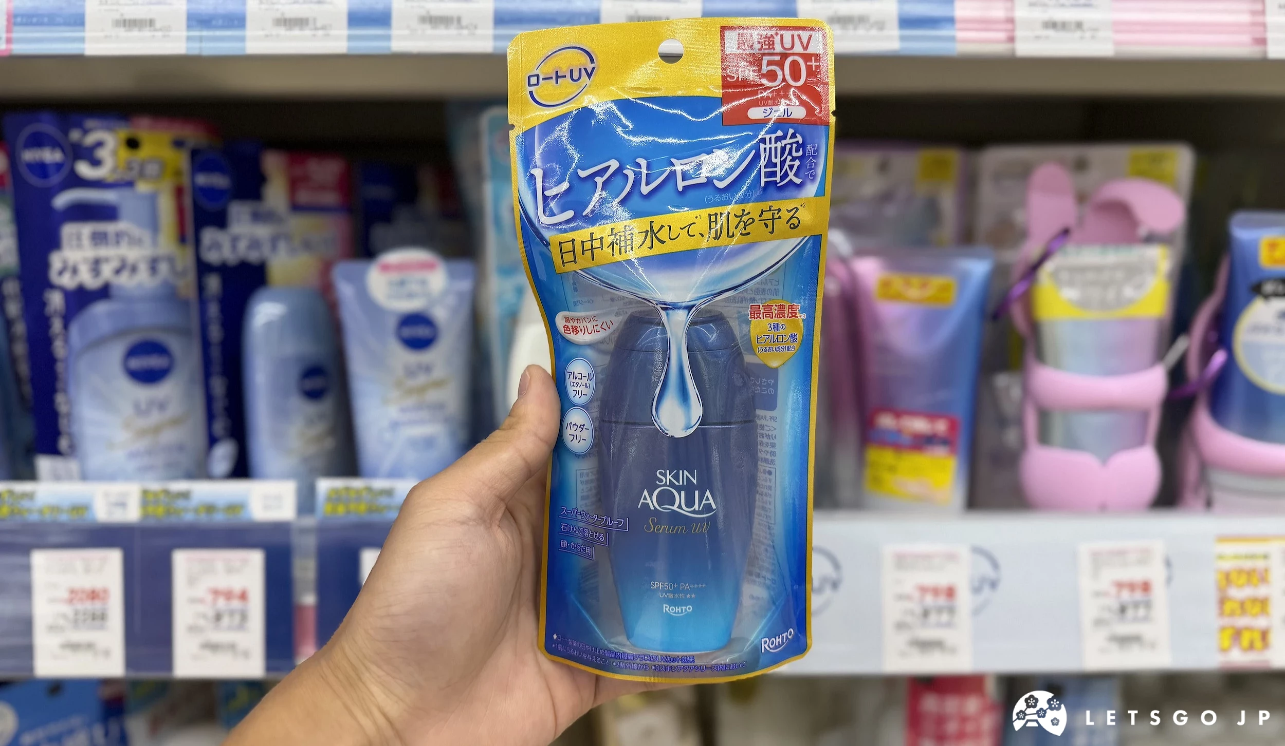 在藥妝店內貨架前,手拿著藍色的防曬