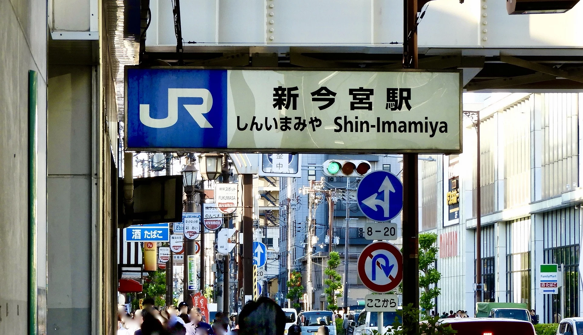 寫著「新今宮站」日文的車站牌,下面是一條行人道。