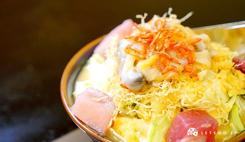 碗中堆放高麗菜、魚肉塊、貝類肉與小蝦乾等食材