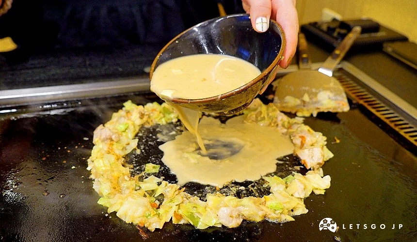鐵板上有一圈文字燒材料,手拿碗倒水到材料中間