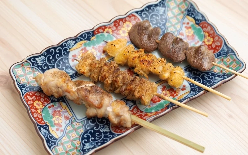 花紋長盤上擺放四串燒烤串,包含雞肉與內臟