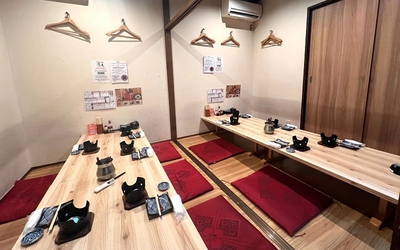 鋪有紅色坐墊的和式長桌座位區，桌上擺放餐具與小型器具