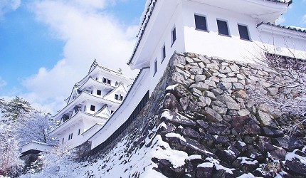 積雪覆蓋石垣與天守閣牆面的冬季雪景