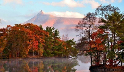 北海道大沼國定公園秋季景色,楓葉林倒映湖面,遠方駒岳山巒映襯紅葉之美