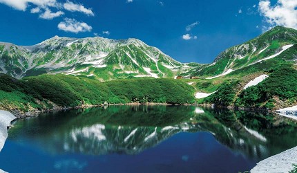 綠色的山與白色的雪交錯著的湖邊風景 width=