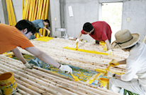 四個人戴著手套低頭正在製作作品